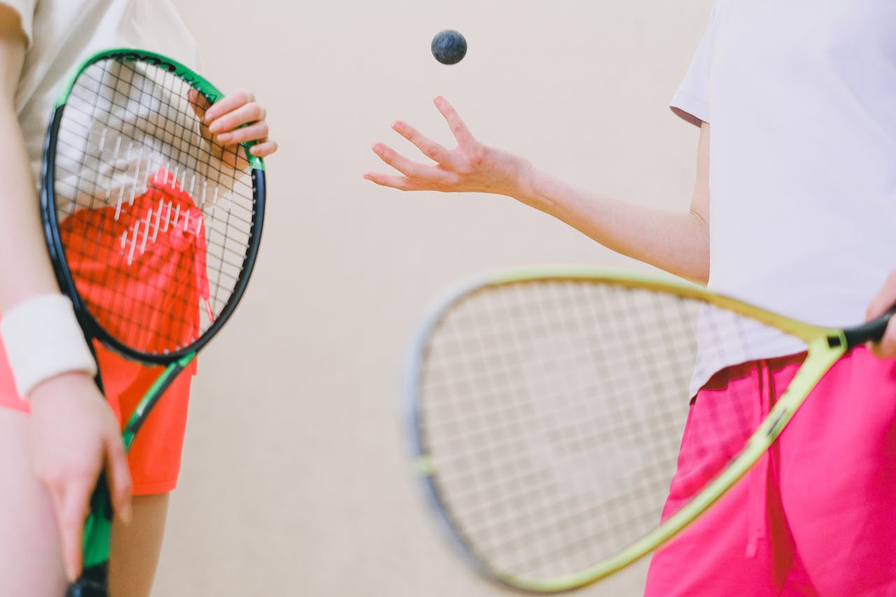 Two tennis players with rackets and a tennis ball, captured in an indoor sports setting.